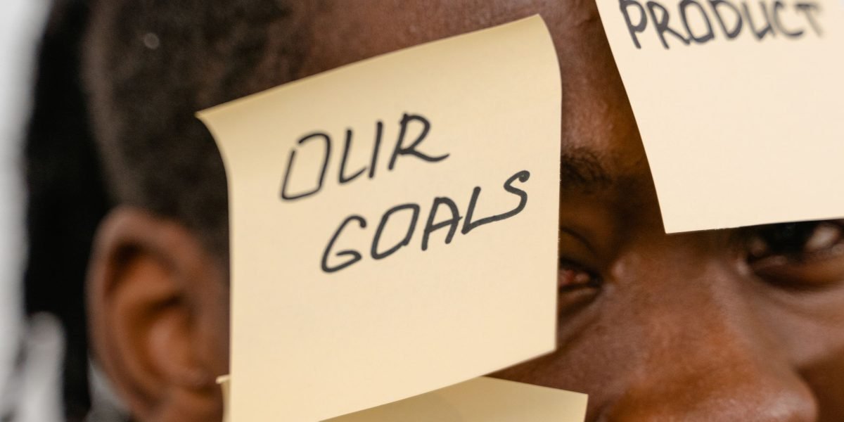 An individual planning or writing down objectives, representing a realistic approach to self-improvement.
