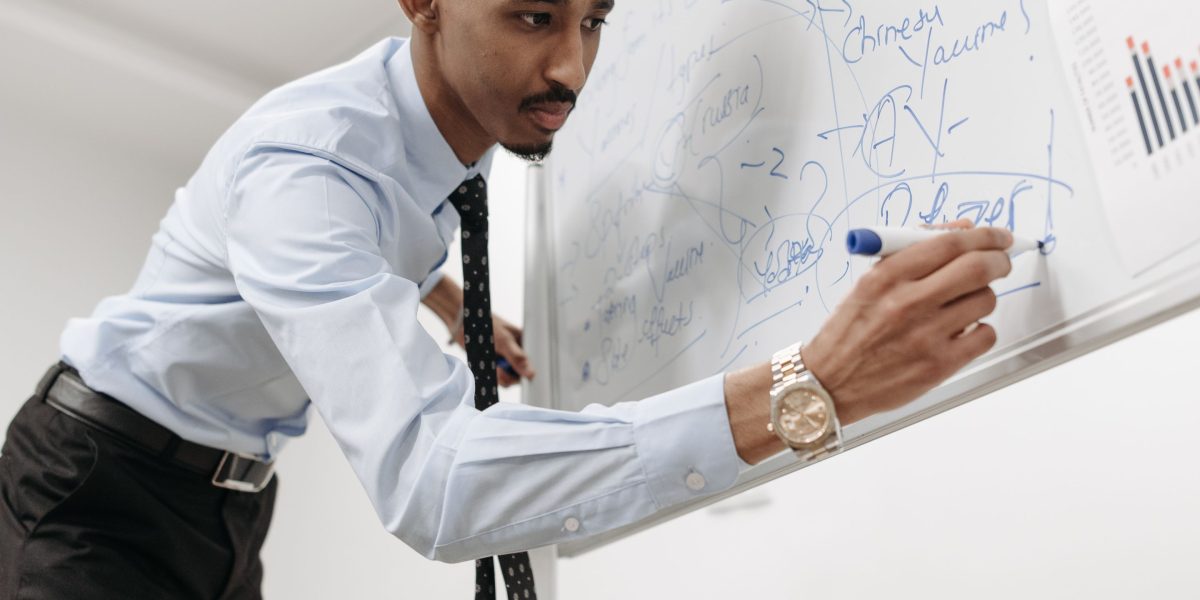 A professional thinking deeply, writing on a whiteboard, demonstrating logical problem-solving and critical thinking.
